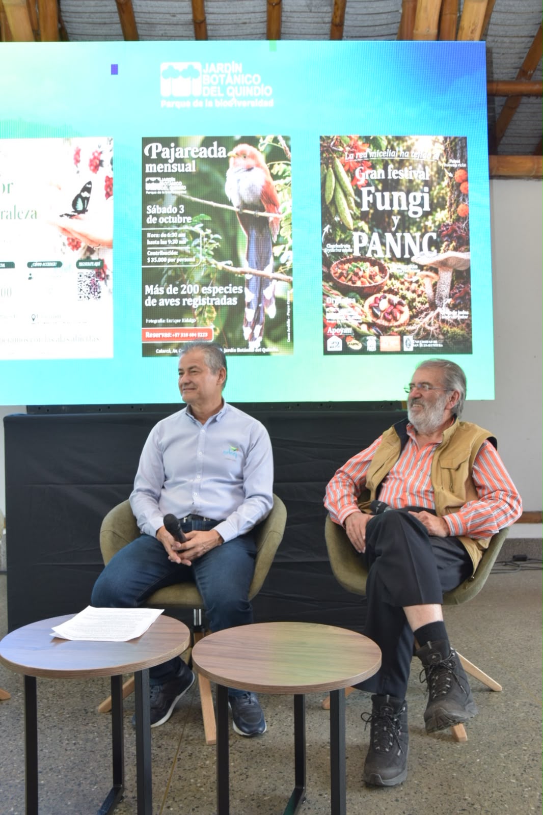 Dos participantes en panel frente a una pantalla del evento